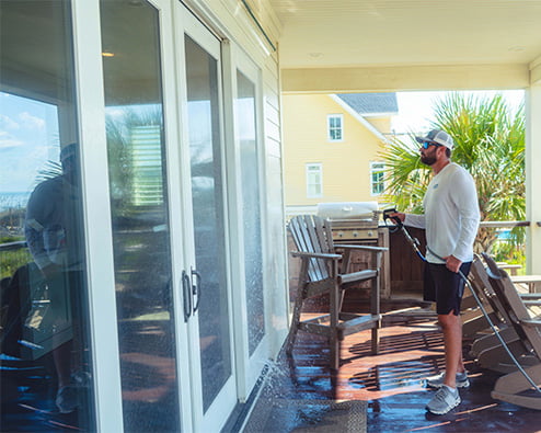 Pressure washing technician cleaning sliding door windows.